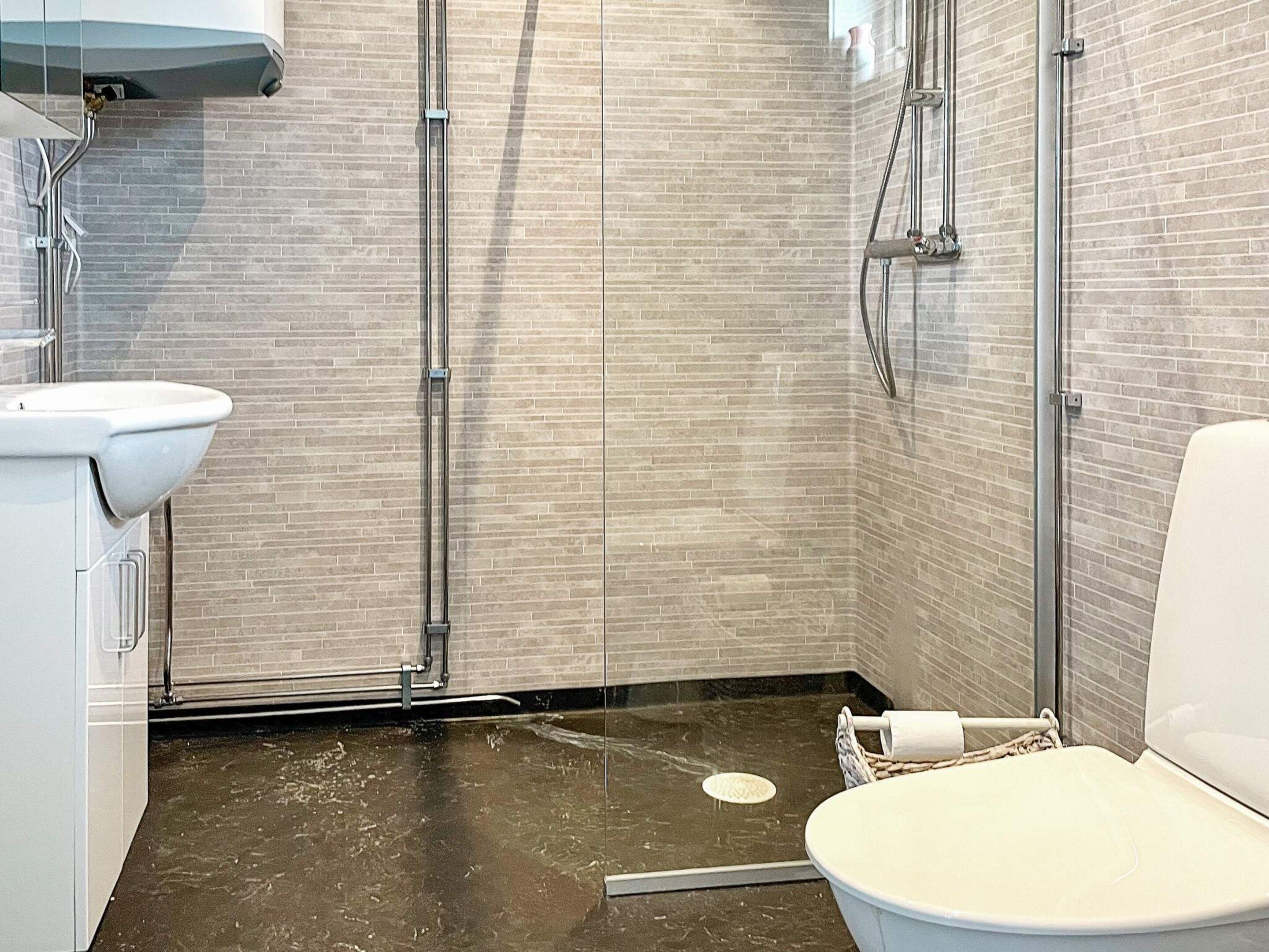 A bathroom with a white sink, a toilet, and a shower area with tiled walls and floor.
