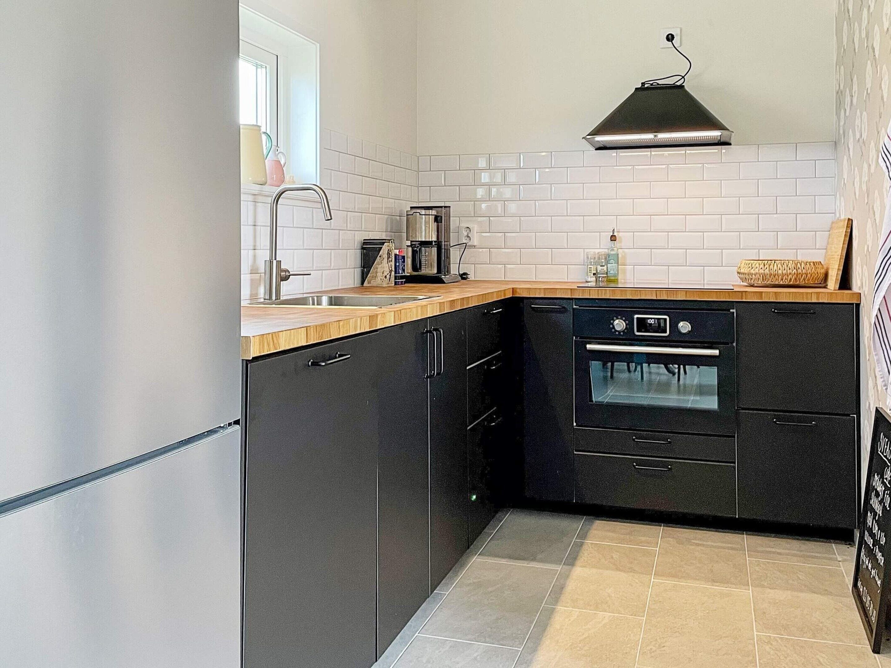 A compact kitchen with a built-in oven, a sink, and a window above the counter.