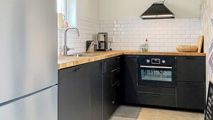 A compact kitchen with a built-in oven, a sink, and a window above the counter.