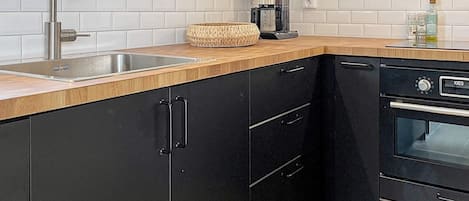 A kitchen with a stainless steel sink, a coffee maker, and a black oven.