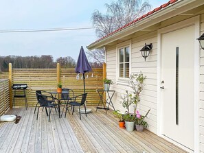 A wooden deck with outdoor furniture, a table, chairs, and potted plants. - 4 Star Holiday Home in Bergkvara (Bergkvara)