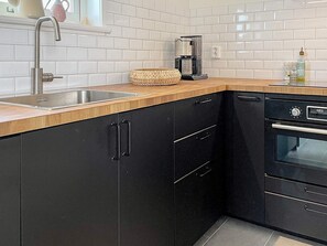 A kitchen with a stainless steel sink, a coffee maker, and a black dishwasher. - 4 Star Holiday Home in Bergkvara (Bergkvara)