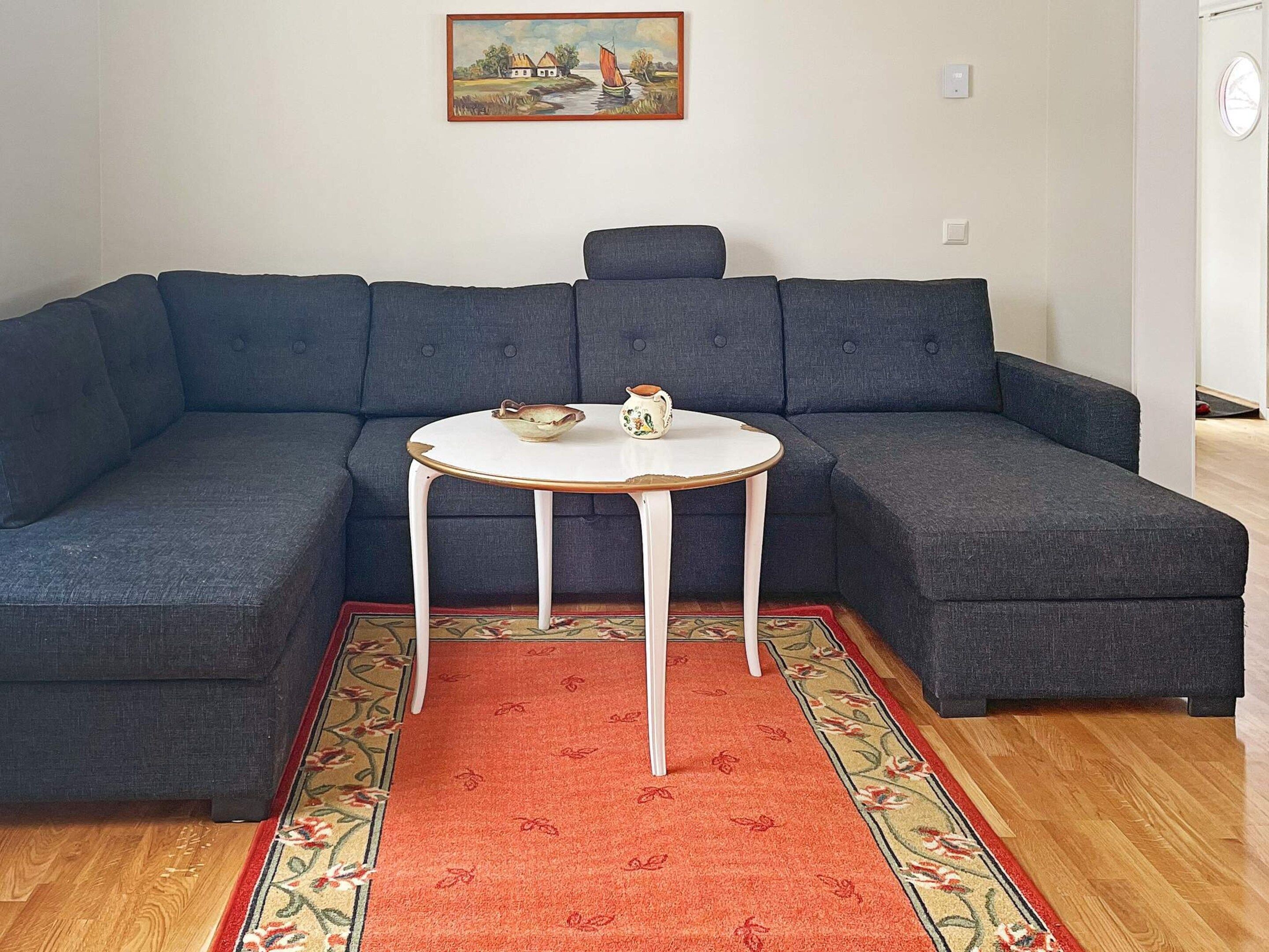 A sectional sofa with a small round table and two decorative bowls.