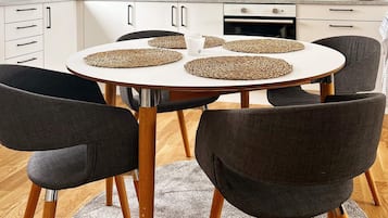Una mesa de comedor redonda con cuatro individuales tejidos, rodeada por seis sillas oscuras de patas de madera.