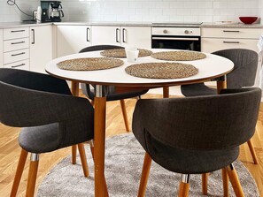 A round dining table with four woven placemats, surrounded by six dark chairs with wooden legs. - 4 Person Holiday Home in Aneby (Aneby)