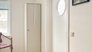 A room with a door, a window with blinds, a chair, and a rug. - 4 Person Holiday Home in Aneby (Aneby)