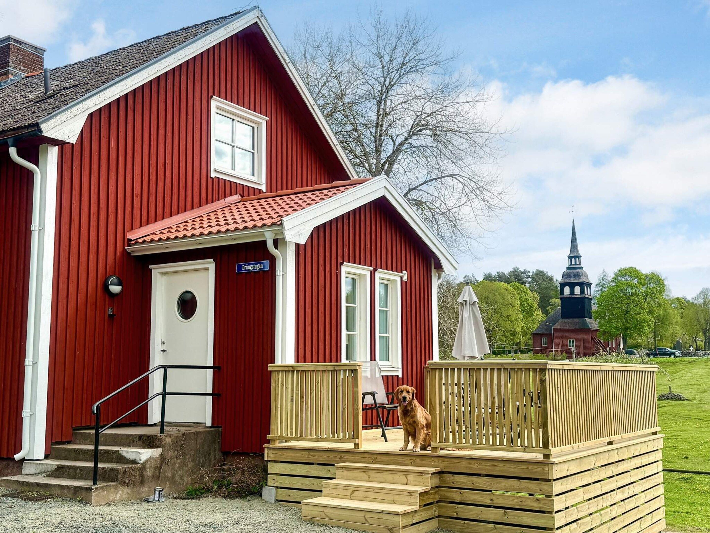 A red building with a wooden deck and a dog.