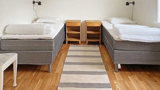 A room with two beds, a small table, and a rug. - 4 Person Holiday Home in Aneby (Aneby)