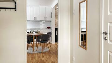 A modern kitchen with white cabinets, a dining area with a round table and chairs, and a wooden floor.