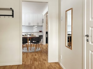 A modern kitchen with white cabinets, a dining area with a round table and chairs, and a wooden floor. - 4 Person Holiday Home in Aneby (Aneby)