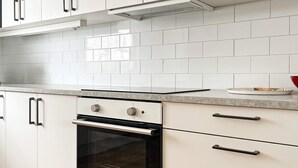 A kitchen with white cabinets, a stainless steel oven, and a tiled backsplash. - 4 Person Holiday Home in Aneby (Aneby)