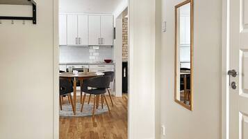 A modern kitchen with white cabinets, a dining area with a round table and chairs, and a wooden floor.