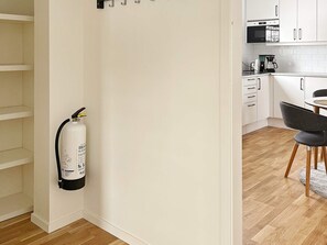 A kitchen with white cabinets, a coffee maker, and a fire extinguisher mounted on the wall. - 4 Person Holiday Home in Aneby (Aneby)