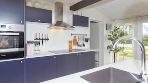 A modern kitchen with a built-in oven, a stainless steel range hood, and a large sink. - 6 Person Holiday Home in Farso (Farso)