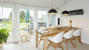 A dining area with a wooden table, white chairs, and pendant lights. - 6 Person Holiday Home in Farso (Farso)