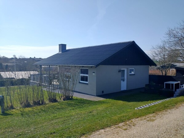 A single-story house with a dark roof, a small front porch, and a well-maintained lawn. - 6 Person Holiday Home in Roslev (Roslev)