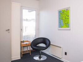 A room with a black chair, a small wooden table with two potted plants, a radiator, and a map on the wall.