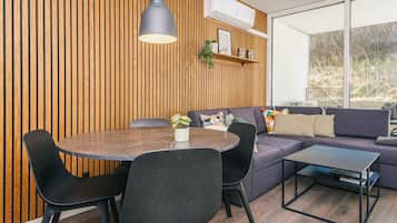 Ein modernes Wohnzimmer mit einem runden Esstisch, schwarzen Stühlen, einem grauen Sofa und einem schwarzen Couchtisch.