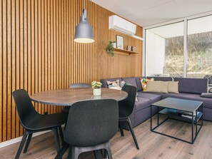 A modern living room with a round dining table, black chairs, a grey sofa, and a black coffee table. - 4 Star Holiday Home in Ringkobing (Ringkobing)