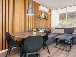 A modern living room with a round dining table, black chairs, a grey sofa, and a black coffee table.