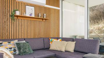 A modern living room with a sectional sofa, a coffee table, and a wooden wall panel.