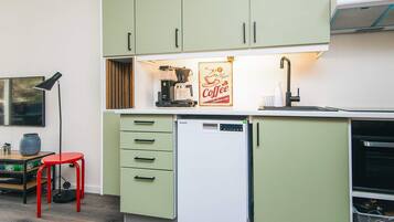 A compact kitchen with green cabinets, a coffee machine, and a dishwasher.