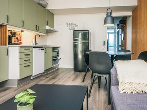 A compact kitchen with a refrigerator, microwave, and coffee machine, a dining area with a table and chairs, and a wall with a motivational quote. - 4 Star Holiday Home in Ringkobing (Ringkobing)