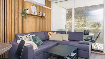 Una sala moderna con un sofá seccional, una mesa de centro y un comedor con una mesa y sillas.