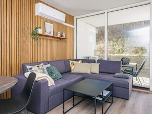 Un salon moderne comprenant un canapé d’angle, une table basse et un coin repas avec une table et des chaises.