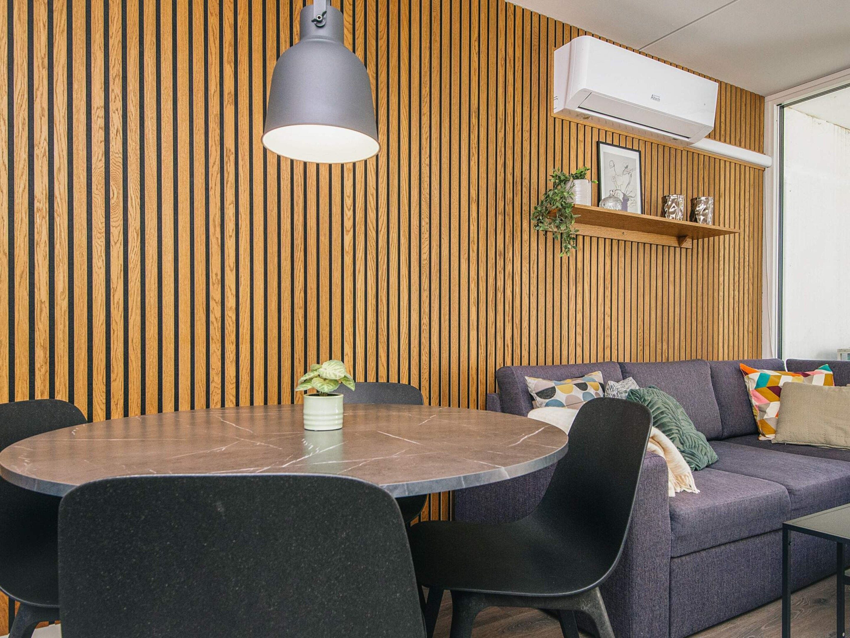 A modern dining area with a round table, black chairs, and a pendant light.