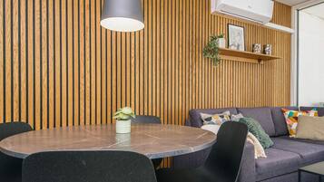 A modern dining area with a round table, black chairs, and a pendant light.