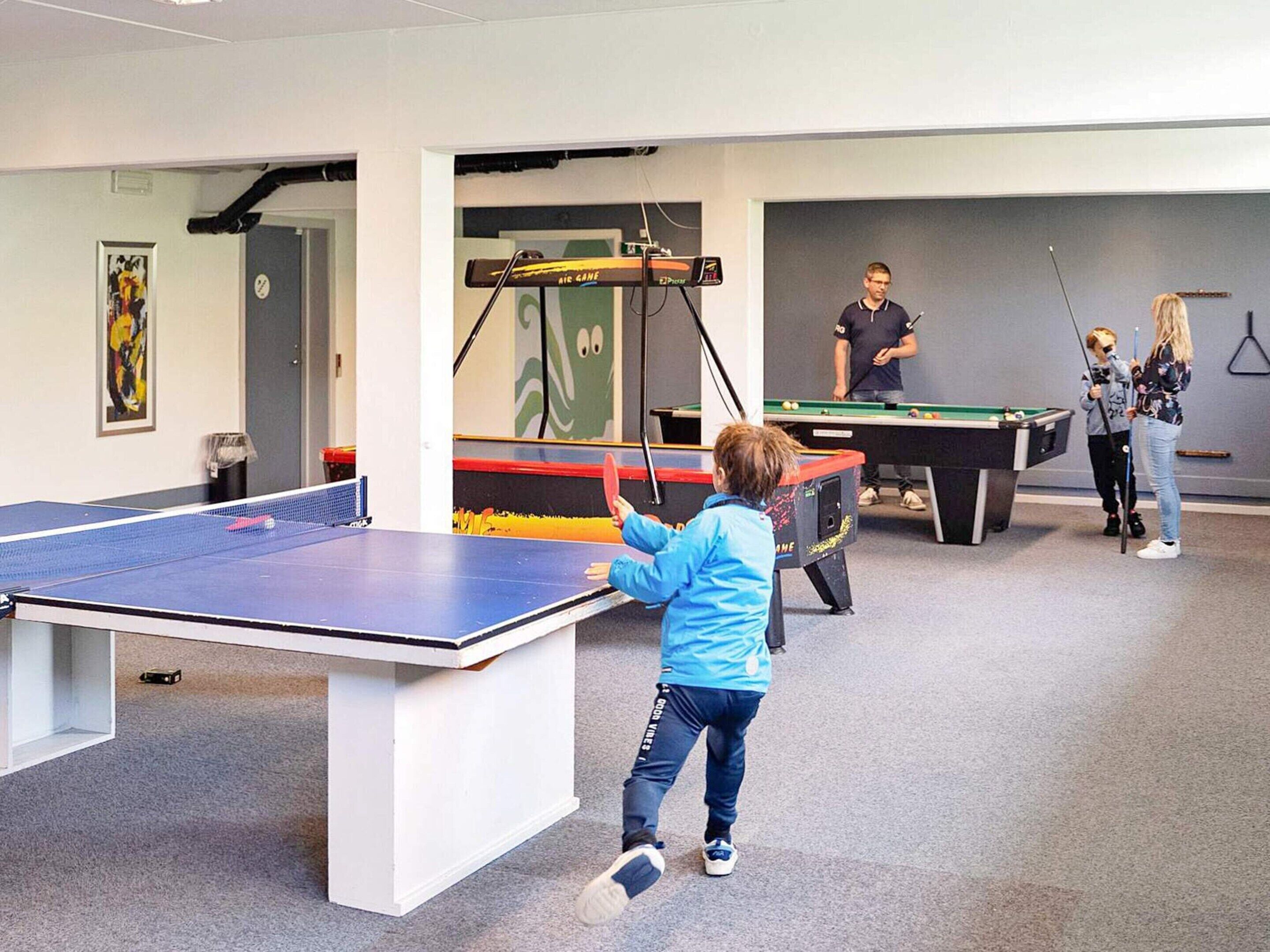 Un área recreativa con mesa de ping pong, mesa de billar y mesa de futbolín.