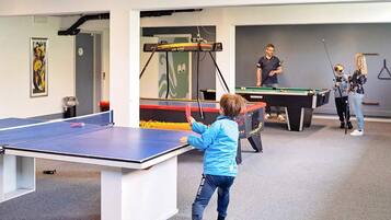 Un área recreativa con mesa de ping pong, mesa de billar y mesa de futbolín.