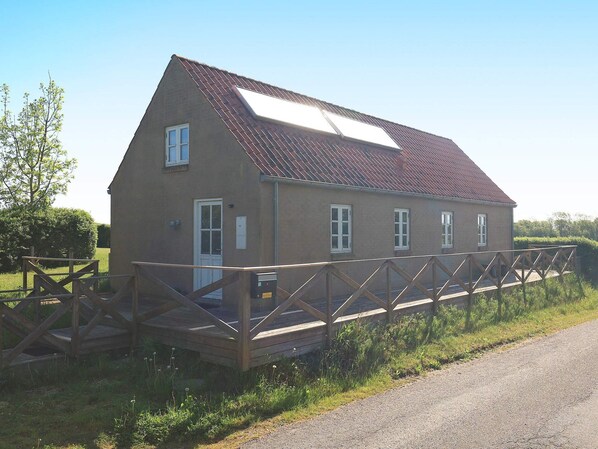 A single-story house with a sloped roof, a wooden deck, and a small porch.