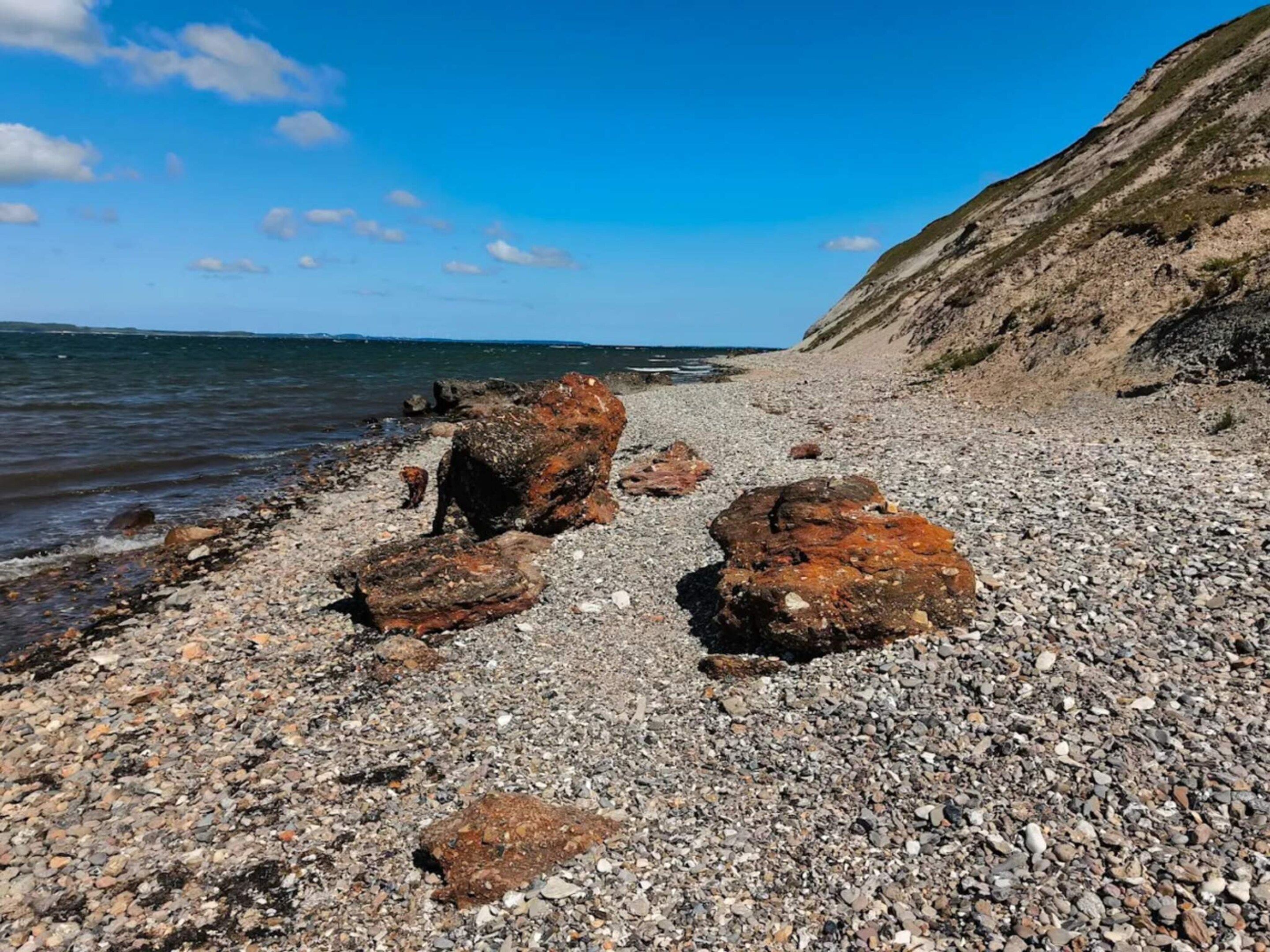 A rocky beach with large boulders and a clear view of the sea.