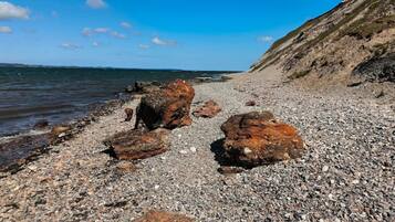 A rocky beach with large boulders and a clear view of the sea.