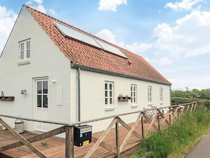 A white building with a red-tiled roof, a wooden deck, and a wooden fence. - 6 Person Holiday Home in Nykobing M (Nykobing Mors)