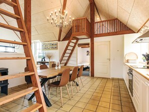 Una cocina espaciosa con una escalera de madera, un comedor con sillas y una araña.