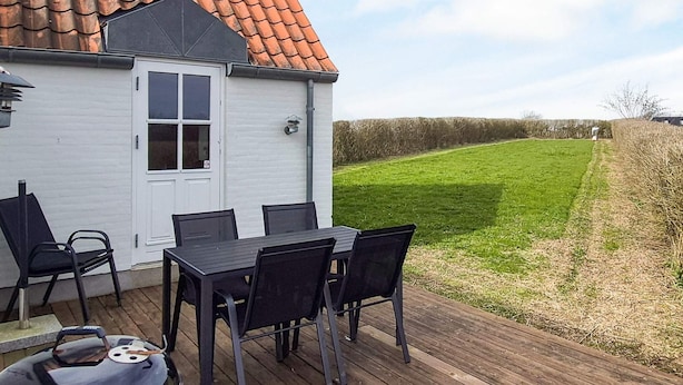 Una casa blanca con techo de tejas y una terraza con mesa y sillas.