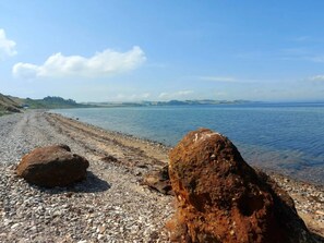 A pebble beach with large rocks and a calm sea under a clear sky. - 6 Person Holiday Home in Nykobing M (Nykobing Mors)