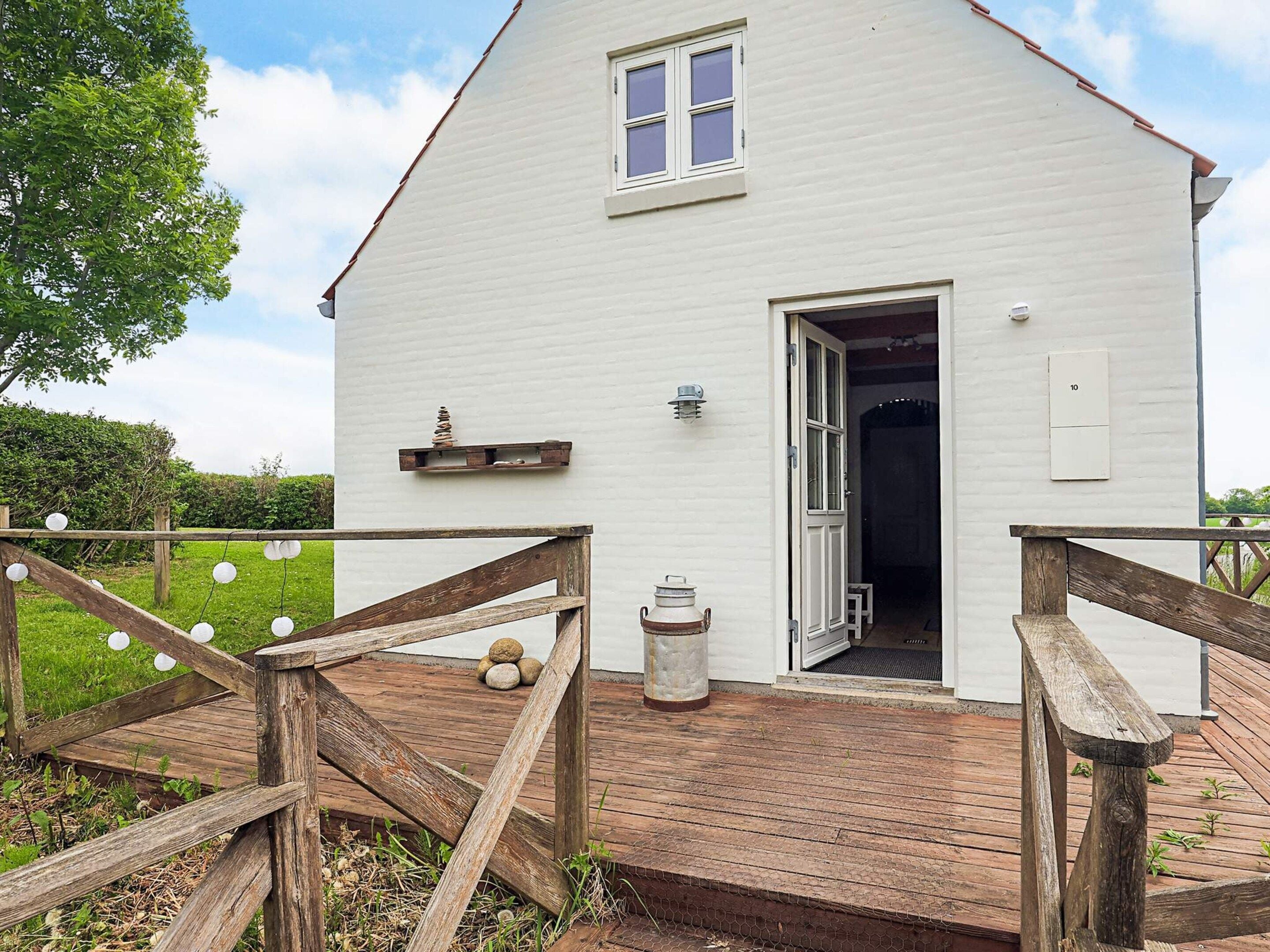 A white building with a wooden deck, a door, and a small window.