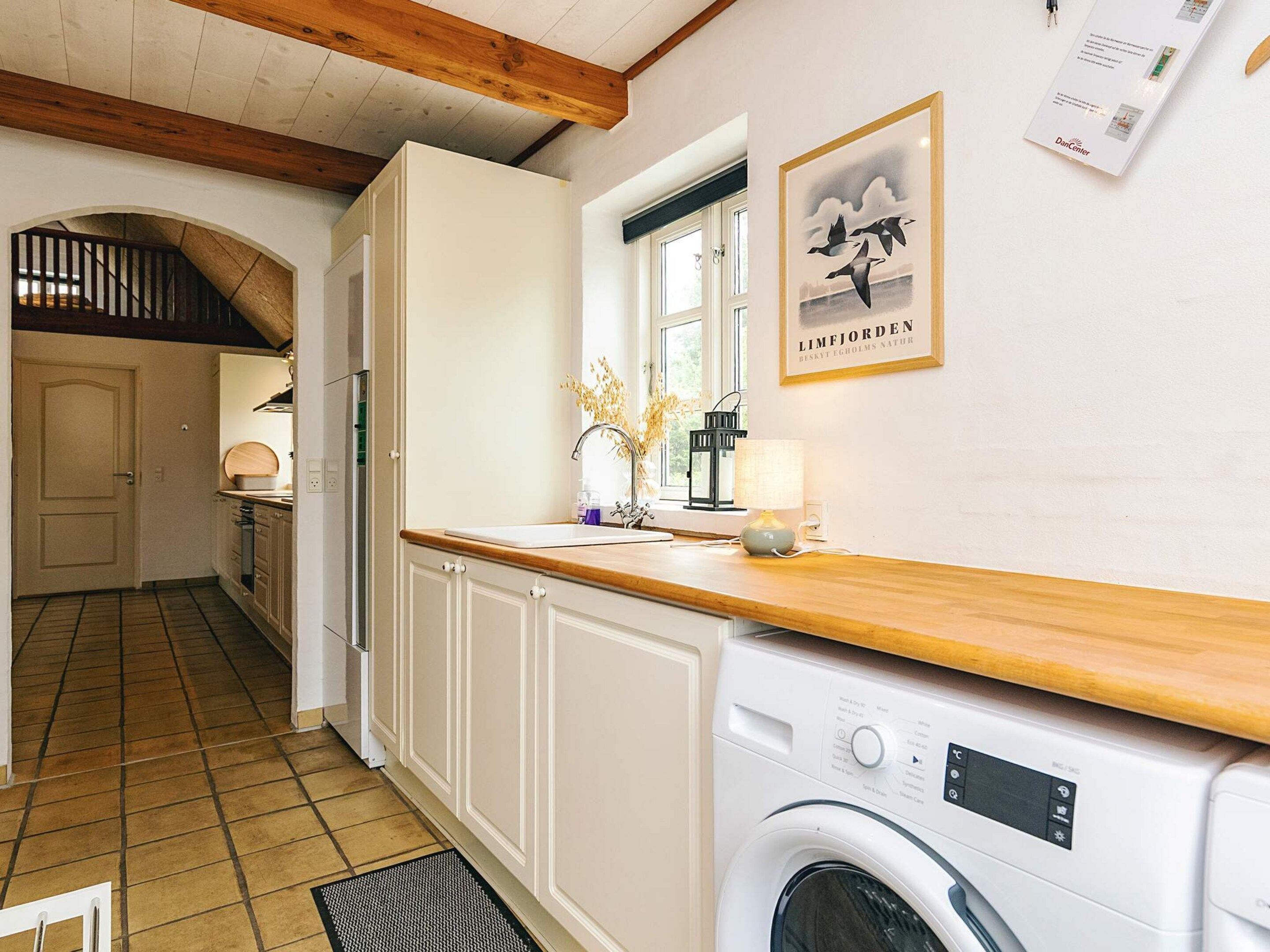 Un cuarto de lavandería con lavadora, un lavabo y una ventana que da al exterior.