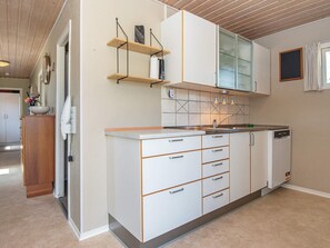 Una cocina moderna con armarios blancos, encimera de madera y lavavajillas integrado.