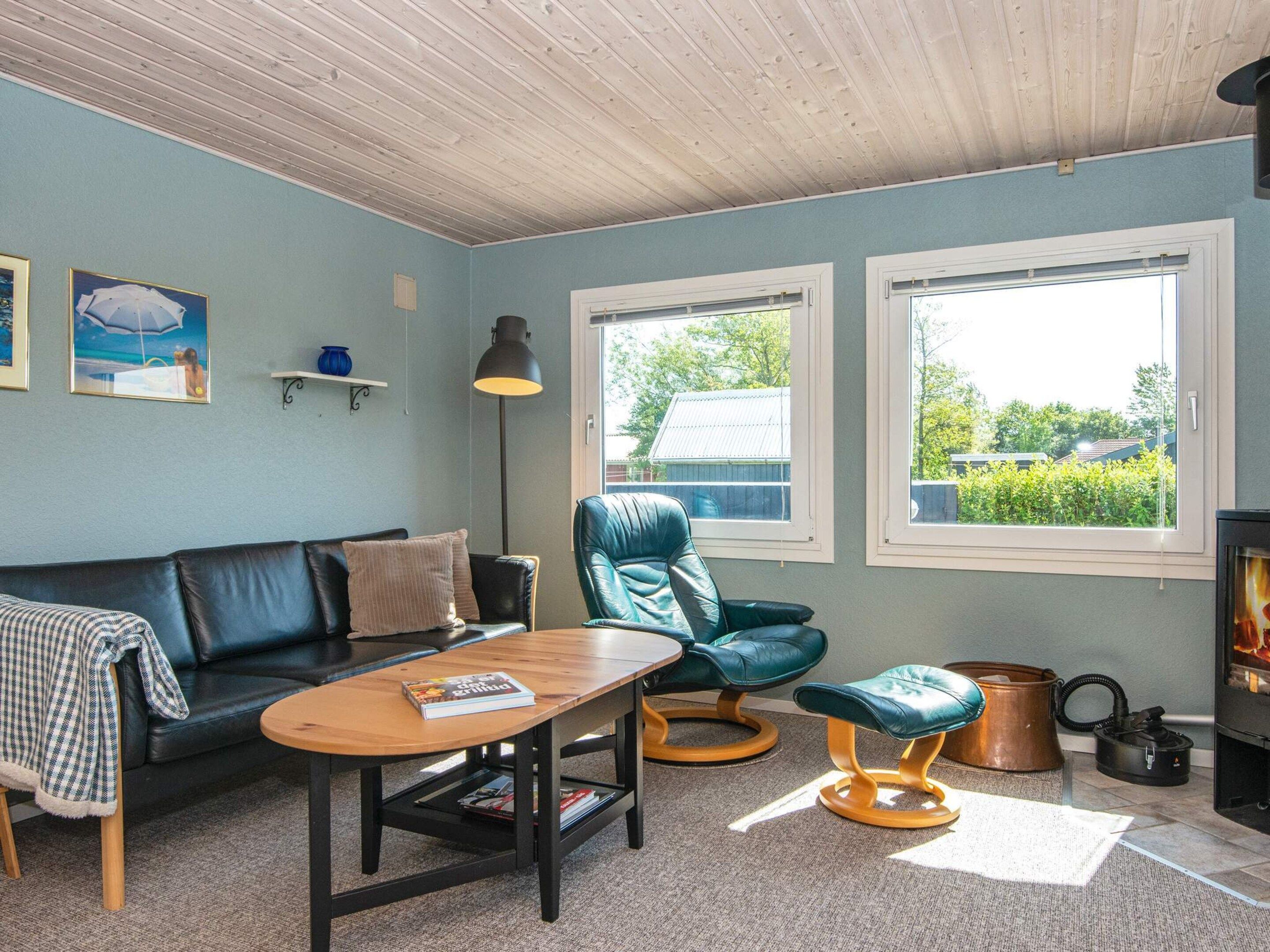 A cozy living room with a sofa, a wooden coffee table, a blue armchair, and a fireplace.