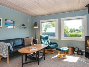 A cozy living room with a sofa, a wooden coffee table, a blue armchair, and a fireplace. - 6 Person Holiday Home in Hemmet (Hemmet)