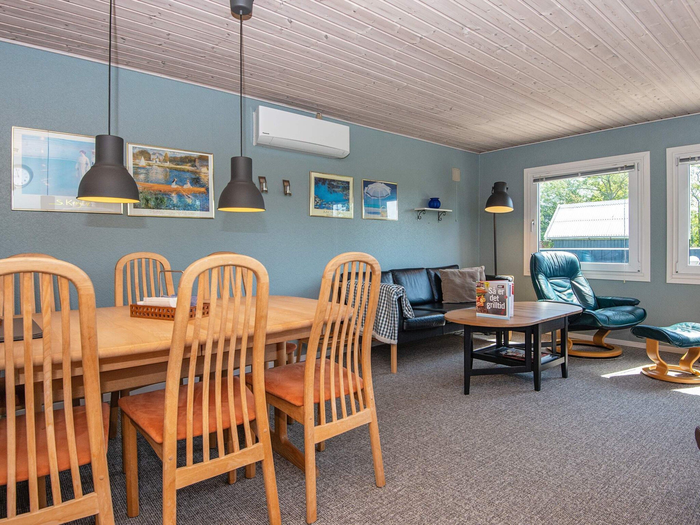 Ein Zimmer mit Esstisch, Stühlen, einer Couch, einem Lesesessel und Bildern an den Wänden.