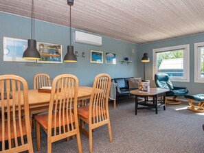 Une pièce comprenant une table à manger, des chaises, un canapé, un fauteuil de lecture et des œuvres d’art accrochées aux murs.