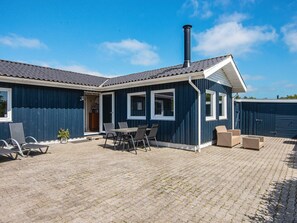 A house with a patio area featuring a table and chairs, a chimney, and a covered entrance. - 6 Person Holiday Home in Hemmet (Hemmet)