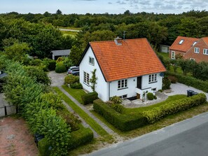 A white house with a red roof, surrounded by greenery and a paved driveway. - 6 Person Holiday Home in Bindslev (Bindslev)