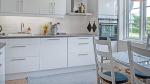 A modern kitchen with white cabinetry, a built-in oven, and a window providing a view of the outdoors. - 6 Person Holiday Home in Bindslev (Bindslev)